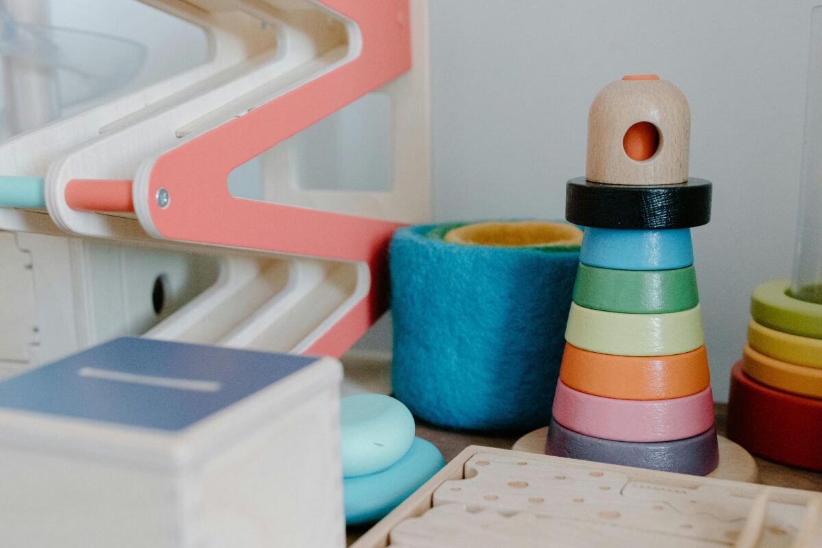 An image of toys including a wooden marble run, wooden stacking rings, felt stacking cups, and wooden dominoes